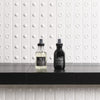 Thumbnail for Two bottles of Davines hair care products on a black surface with a white tiled wall background.