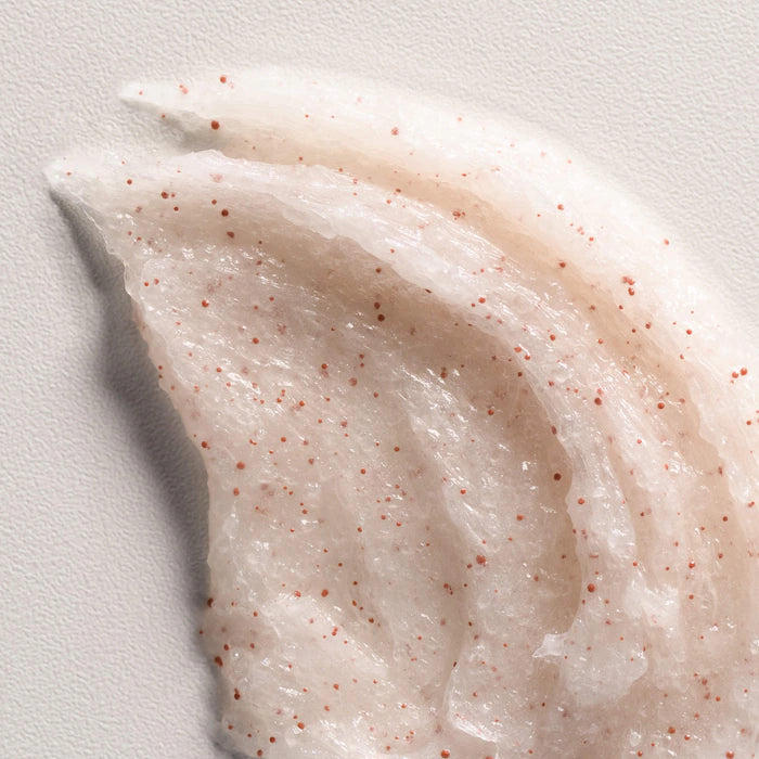 Close-up of a swatch of cream with red specks on a light gray background