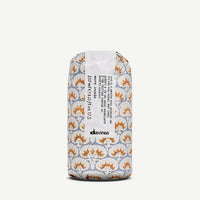 Thumbnail for Davines Wette Celand 250ml roll-on bottle with a patterned paper sleeve featuring orange and white floral motifs on a light gray background, set against a plain off-white studio backdrop.