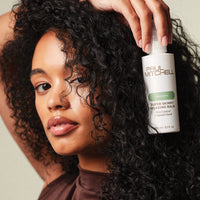 Thumbnail for Woman holding a bottle of Paul Mitchell hair product with curly hair.