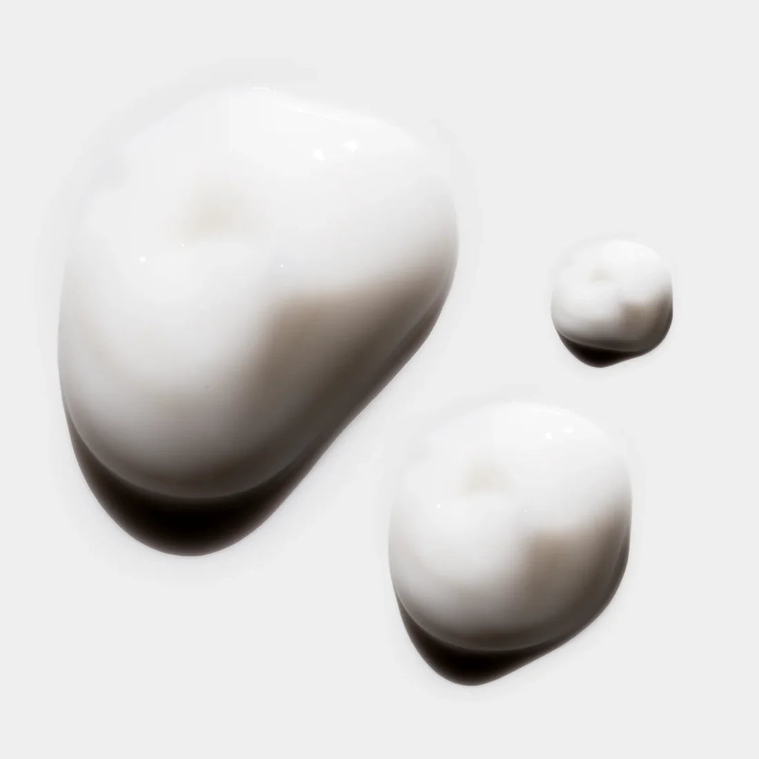 Three white dollops of AlumierMD HydraLight Moisturiser showing its creamy texture on a white background.