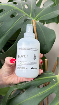 Thumbnail for Hand holding a Davines hair care product bottle against a leafy background