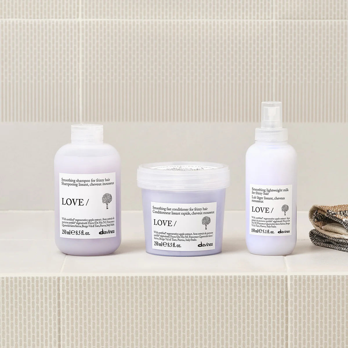 Three Davines hair care products on a bathroom shelf with a tiled wall background.