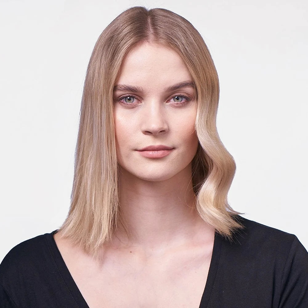 Woman with styled blonde hair against a plain background