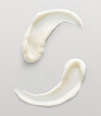 Thumbnail for Two thick, creamy white swaths of lotion or cream arranged in a curved, S-like pattern on a light gray background.